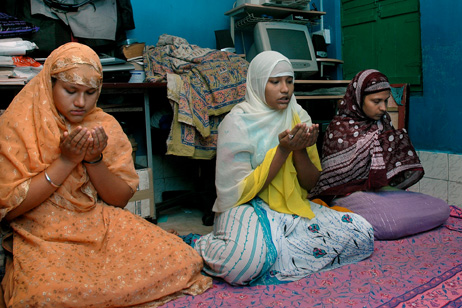 Shakila, Sanno and their sister, from left, pray in  their two-roomed flat.