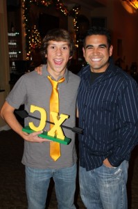 A kid getting an award with an assistant coach